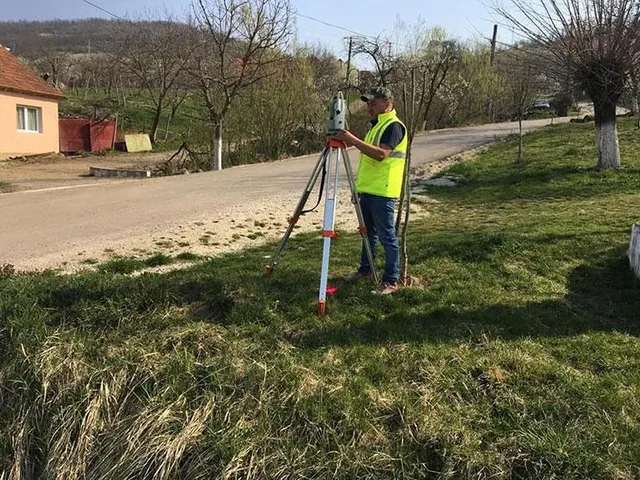 Inginer topograf PROMETER M&G efectuând o măsurătoare cu stație totală pe marginea unui drum rural