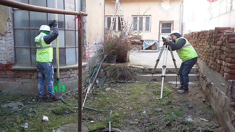 Doi colegi din echipa PROMETER M&G efectuând o măsurătoare într-o curte interioară